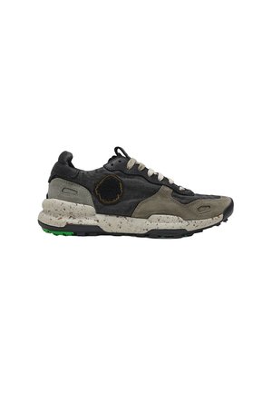 Zapatilla negra y gris con cordones, suela blanca salpicada y un parche circular negro en el lateral, vista desde el exterior.