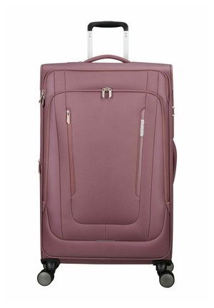 Grande valise souple mauve avec poignée télescopique, poches avant zippées, quatre roulettes pivotantes et logo de la marque American Tourister à l'avant.