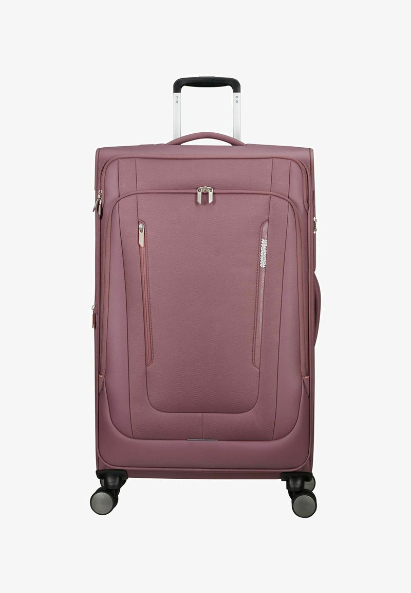 Großer mauvefarbener Weichschalenkoffer mit Teleskopgriff, vorderen Reißverschlusstaschen, vier Rollen und dem American Tourister Markenzeichen vorne.