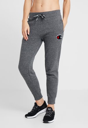 Pantalon de jogging slim gris foncé avec taille à cordon et logo Champion sur la cuisse, porté avec des baskets noires Under Armour.