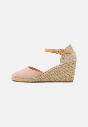 Wedge heel shoe with a pink suede upper, beige patterned back, and a woven jute sole. Features an adjustable tan ankle strap.
