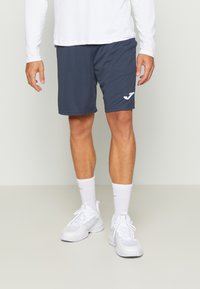 Męskie szorty sportowe w granatowym kolorze, wykonane z lekkiego materiału, z haftowanym białym logo na lewej nodze i prostym, eleganckim wzornictwem.