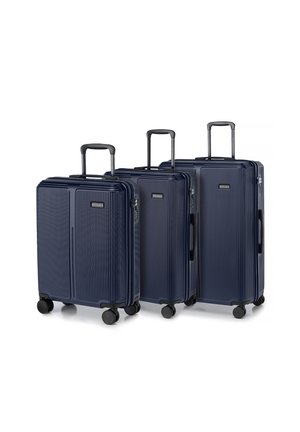 Three navy blue hard-shell suitcases with vertical grooves, retractable handles, and four wheels for mobility, varying in size.