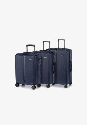 Tre valigie rigide blu navy con scanalature verticali, manici retrattili e quattro ruote per la mobilità, di diverse dimensioni.
