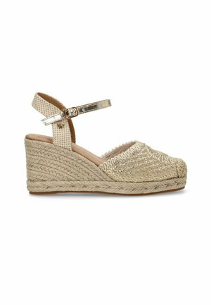 Sandalias de cuña beige con una base de paja trenzada, una parte superior de tejido texturizado y un detalle de tira metálica en el tobillo. Punta cerrada con un forro suave.