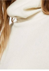 Crèmekleurige turtleneck trui van zacht, gestructureerd materiaal met een losse, gevouwen kraag en een subtiel breipatroon.