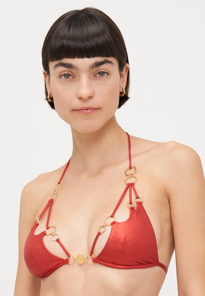 Red bikini top made of shiny fabric with gold circular accents and links, featuring a halter neck design and minimal coverage.