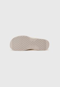Sneaker outsole, textured with a honeycomb pattern, light beige color, smooth edges, rounded toe, marked brand logo on side.