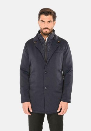 Cappotto blu navy dal design su misura, con colletto a revers, chiusura a bottoni e tasche laterali. Tessuto liscio con minime rifiniture.