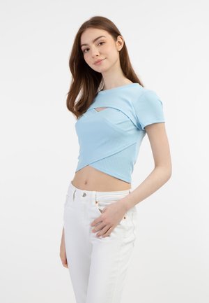 Light blue ribbed crop top with a cut-out detail at the front, featuring short sleeves and a fitted design. Paired with white jeans.