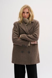 Rudas houndstooth vilnonis paltas su dvigubos užsegimo dizainu, dideliais iškirptais atlapais ir dviem priekinėmis kišenėmis. Poruotas su derančia megzta turtlenecko formos palaidine.