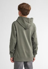 Sudadera verde con un tejido texturizado, mangas largas y capucha con cordón, que cuenta con un bolsillo tipo canguro y puños y dobladillo acanalados.