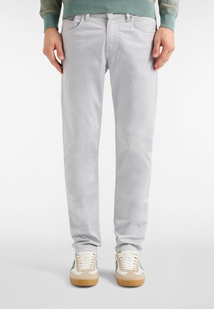 Jasnoszare chinosy o gładkiej fakturze, z pięcioma kieszeniami i standardowym pasem. W połączeniu z białymi i beżowymi butami sportowymi.