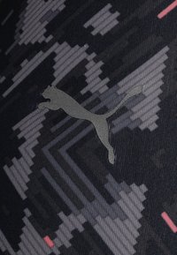Legginsy Puma z czarnej, teksturowanej tkaniny z pikselowym wzorem oraz dyskretnym szarym logo z boku.
