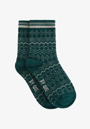 Türkise Socken mit einem Muster aus Rauten und Wellen in Grau. Strickstruktur mit horizontalen Streifen am Bund.