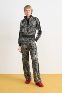 Tuta in stampa leopardata realizzato in tessuto morbido con dettagli neri. Include una giacca con zip e pantaloni dalla vestibilità ampia. Calzature rosse completano il look.