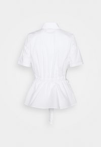 Chemise blanche à manches courtes avec un design péplum, dotée d'un col et d'une taille élastiquée pour un effet froncé. Texture lisse et nette.
