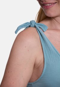 Hellblaues, ärmelloses Top aus weichem, strukturiertem Stoff mit verstellbaren Schulterbändern zum Binden. Das Design hat eine lockere Passform.