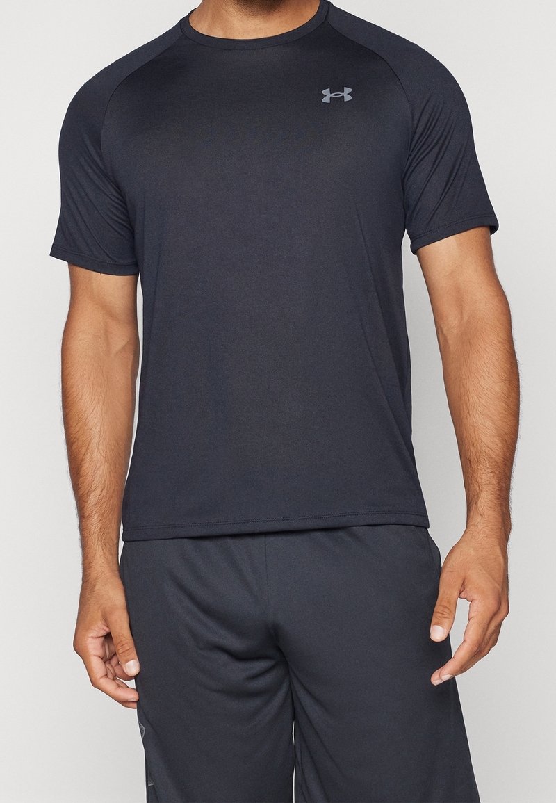 Camiseta deportiva negra de manga corta, hecha de tejido que absorbe la humedad. Presenta un logo gris en la parte superior del lado izquierdo del pecho.