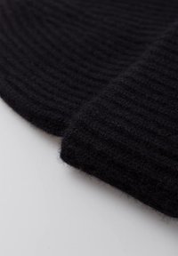 Tessuto di lana nero con una texture a coste, caratterizzato da due sezioni sovrapposte. Finitura morbida con una leggera lucentezza, che mette in risalto il suo colore ricco.