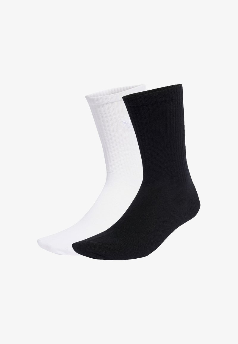 Crno-bijele pamučne čarape do gležnja s rebrastom teksturom. Crna čarapa je s desne strane, bijela s lijeve, obje imaju bešavni dizajn na prstima.