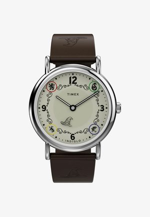 Montre-bracelet Timex avec cadran rond, aiguilles noires, quatre symboles de maison colorés, et un bracelet en cuir marron embossé d'un chapeau de sorcier.