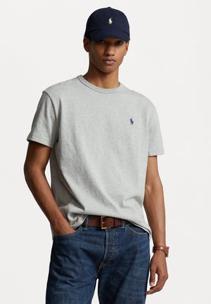 Gray cotton t-shirt with a crew neck, featuring a small navy logo. Paired with dark blue denim jeans and a brown leather belt.