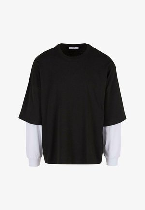 Top nero a maniche corte con maniche lunghe bianche sovrapposte, realizzato in tessuto morbido, con scollatura rotonda e vestibilità comoda.