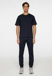 Mörkblå bomulls t-shirt med korta ärmar, i kombination med matchande joggarbyxor med elastiska hörn och dragsko i midjan.