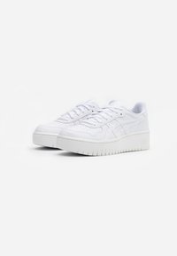 White sneakers made of smooth material, featuring a rounded toe, lace-up design, prominent sole, and subtle brand accents.