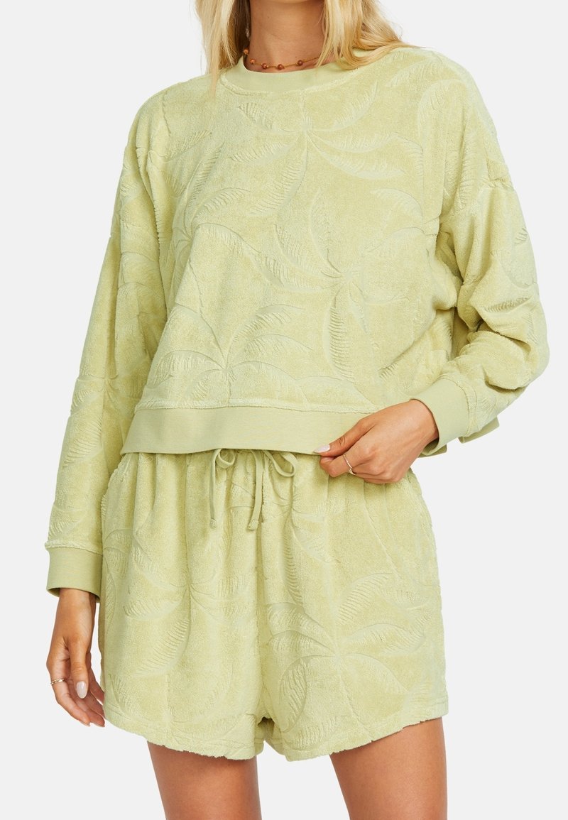 Světlý zelený froté lounge set s embosovanými vzory listů; obsahuje dlouhý rukáv a kraťasy na stažení. Měkká textura, pohodlný střih.