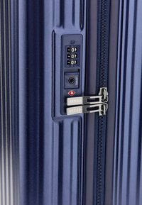 Navy-Hartschalenkoffer mit strukturiertem Finish, einem TSA-zugelassenen Schloss und doppelten Metallreißverschlüssen mit "GUESS"-Branding.