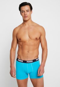 Turquoise boxer briefs with a black waistband featuring the "PUMA" logo. Made of stretchy fabric, designed for comfort and fit.