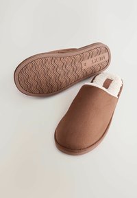 Barna slip-on papucsok, puha, bolyhos fehér béléssel. A külső sima, míg az talp hullámos textúrával rendelkezik a tapadás érdekében.