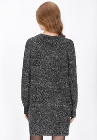 Szürke kötött pulóverruha hosszú ujjakkal, texturált anyagból, kerek nyakkivágással, enyhén bő szabású és térd feletti szegéllyel.