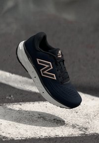 Navy running shoe with mesh upper and rose gold accents. Features a cushioned white sole and a textured pattern on the upper.