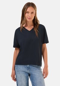 Námořnická modrá tričko s krátkým rukávem a výstřihem do V, s pohodlným střihem a bezšvovým designem ramene. Hladký bavlněný materiál, jemně texturovaný.