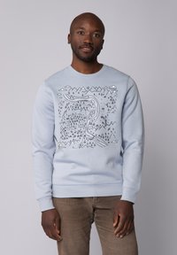 Lichtblauwe sweatshirt met een handgetekend ontwerp van een berg en rivier in zwart. Ribgebreide manchetten en onderrand. Zacht katoenmateriaal.