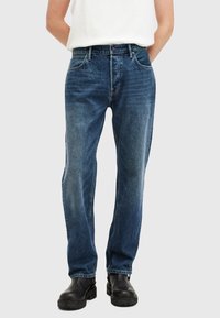 Jeans in denim blu scuro con taglio dritto, caratterizzati da un design a cinque tasche, passanti per cintura e una leggera trama sbiadita.