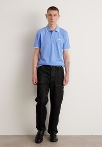 Svetlo modra polo majica z belimi detajli, v paru z temno strukturiranimi hlačami in črnimi čevlji, s slim fit krojem in priložnostnim videzom.