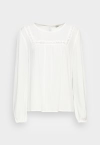 Blusa bianca a maniche lunghe con scollo rotondo, dettagli in pizzo sull'impervia e tessuto testurizzato. Presenta polsini elasticizzati e apertura a occhiello sulla schiena.