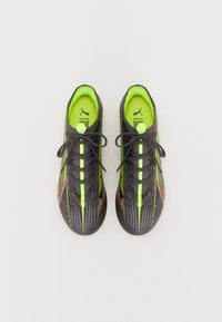 Zapatillas deportivas negras con una superficie texturizada, acentos en verde neón, un diseño vibrante y cordones negros que ofrecen un ajuste ceñido.
