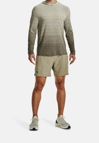 Felpa leggera grigia a maniche lunghe con texture a righe, abbinata a pantaloni corti beige e scarpe da ginnastica grigie chiare. Logo Under Armour sui pantaloni corti.