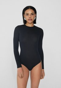Černý bodysuit s dlouhými rukávy a vysokým výstřihem, s hladkou strukturou. Sedí těsně, má plnou pokrytí a žádné viditelné zapínání.