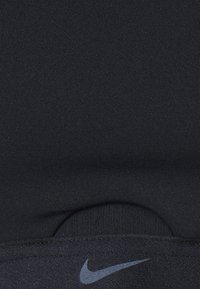 Schwarzer Sport-BH aus dehnbarem Stoff mit glatter Textur, ausgestattet mit einem dezenten Nike-Logo in Dunkelgrau auf dem Band.