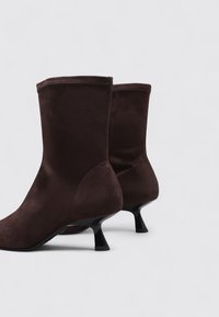 Bottines en suede marron avec une texture douce, un bout pointu et de modestes talons kitten noirs. Surface lisse, design simple, sans matériel visible.