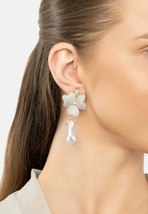Gold-tone earrings designed as flowers, featuring sparkling crystals and a drop-shaped pearl accent. Textured petals provide visual interest.