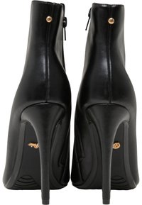 Botas de tobillo de cuero negro con un diseño elegante, puntera afilada, tacón alto de aguja y un detalle dorado cerca de la cremallera. Suela texturizada para un mejor agarre.