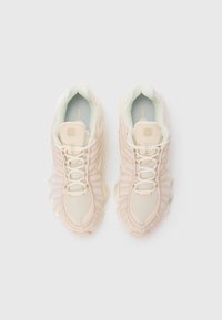 Light pink athletic shoes with textured fabric, mesh panels, and a chunky translucent sole. Features rounded laces and logo accent on tongue.