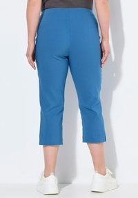 Pantalones cortos azules de un material suave y elástico. Presentan una cintura ajustada y una ligera abertura en el dobladillo, combinados con zapatillas blancas de plataforma.
